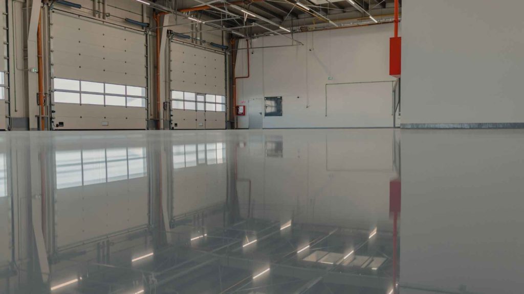 Finished light grey epoxy floor inside an industrial building with roller doors