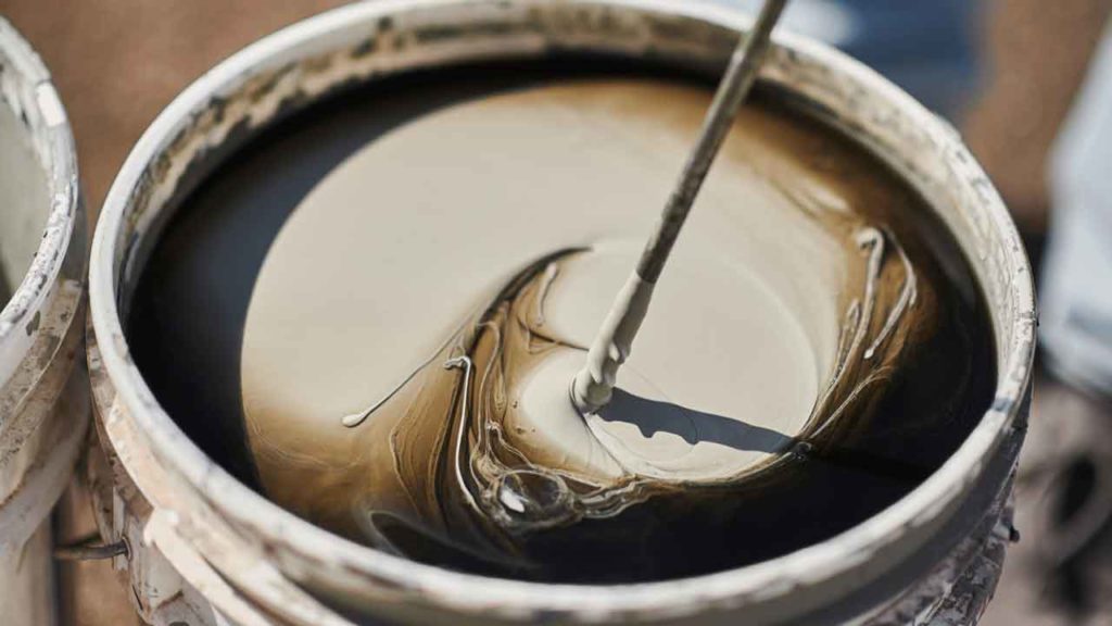 Close-up of epoxy resin being mixed in a bucket with a mixing paddle