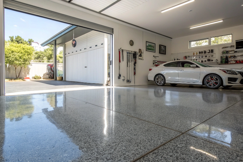 Polished concrete overlay garage floor Toowoomba showing glossy reflective finish with organized tools and white car